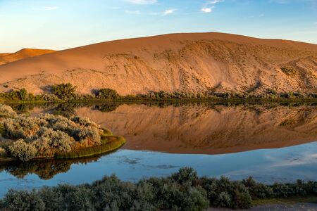 Desert oasis of water with vegetation along with blue sky and clouds at Bruneau Dunes, Idaho.の写真素材
