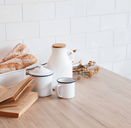 The table with a book, a cup of coffee, a jar of milk and a French bread with sunshine in morning, Beauty concept of beverage and food with relaxation and refreshment during day. Cafe shop.の写真素材
