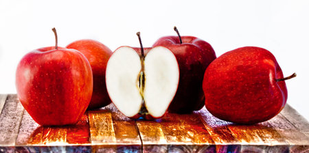 Four red apples and half an apple on wooden cutting boardの写真素材