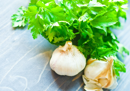 Garlic and a bunch of parsley on woodboardの写真素材