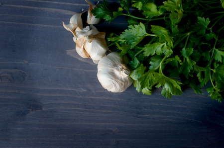Garlic and a bunch of parsley on woodboardの写真素材