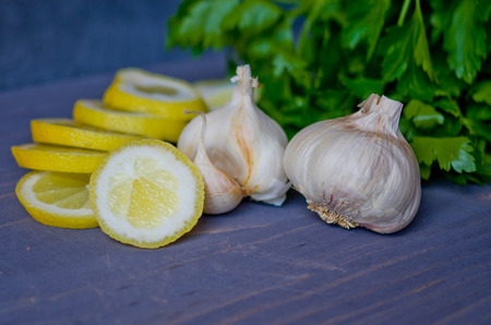 Garlic lemon and a bunch of parsley on a woodboardの写真素材