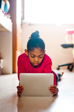 young girl having fun studying with a tablet in her room.の写真素材