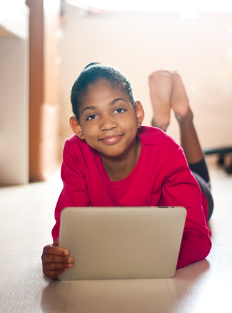 young girl having fun studying with a tablet in her room.の写真素材