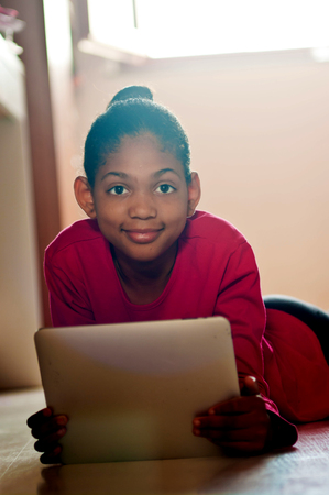 young girl having fun studying with a tablet in her room.の写真素材
