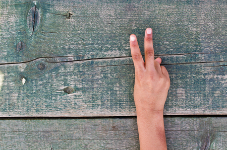 a hand tells us the right number, one, two, three, four, five out of an aged wooden tableの写真素材