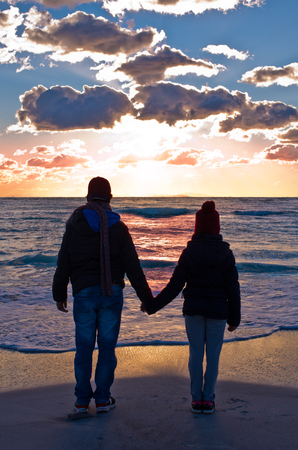 two people watching the sunset who goes to sleep in the seaの写真素材