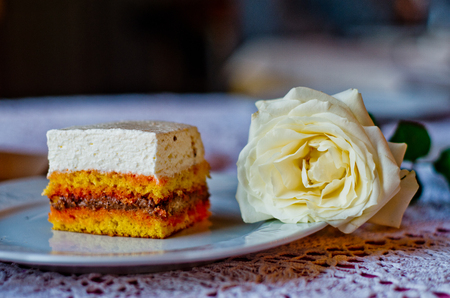 slice of cake with cream, sponge cake, chocolate and strawberry juice and white roseの写真素材