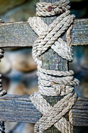 nodes of an old rope holding together of the strips of wood of a railingの写真素材