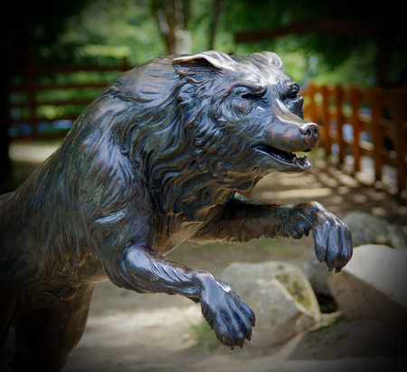 Wolf statue in the park with trees, tourists, families and children