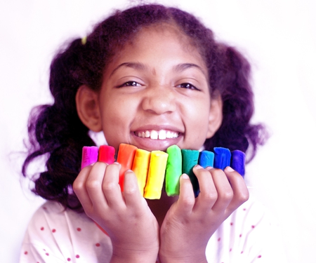 Little girl holds in her hands the dough elements of all colors to make multicolored object modelsの写真素材