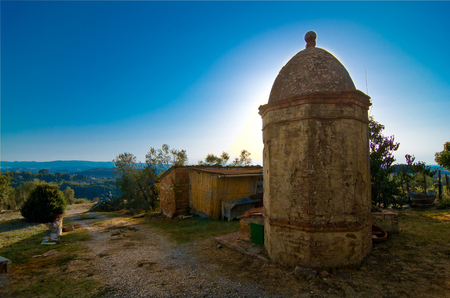 sun rises behind the historic octagonal masonry well in the Tuscan countrysideの写真素材