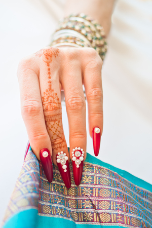 hand with henna tattoo, nails decorated with brilliants and bracelets with precious stonesの写真素材