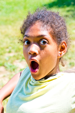 young South American girl looks with amazed expression and eyes wide open in a meadowの写真素材