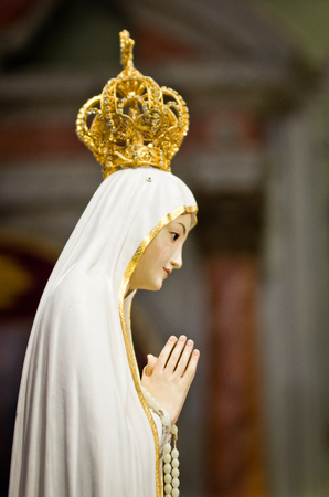 in the baroque church there is the statue of the Madonna with white veil and crown and gold decorationsの写真素材