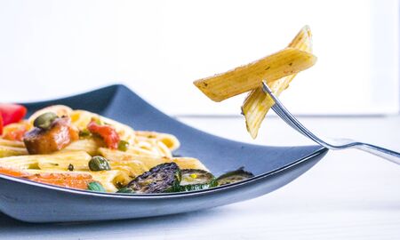 nourishing and healthy pasta, macaroni with colorful and tasty vegetables and capersの写真素材