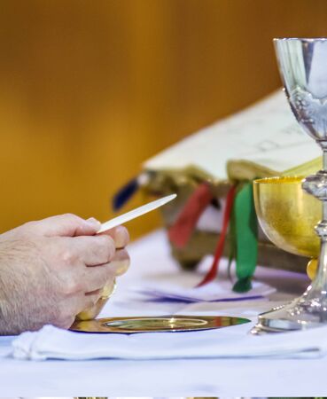 hand of the pope with consecrated host that becomes the body of jesus christ and chalice for wine, blood of christ, in the churches of rome and all over the worldの写真素材