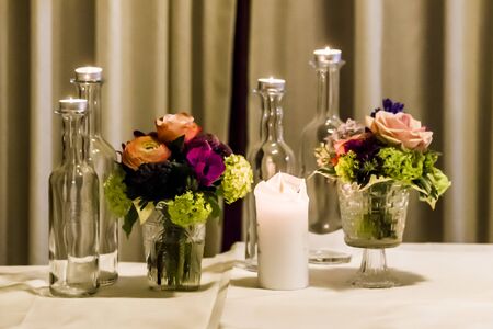 candles, orange, blue and purple flowers and bottles, on the laid table to create the right atmosphere for your partyの写真素材