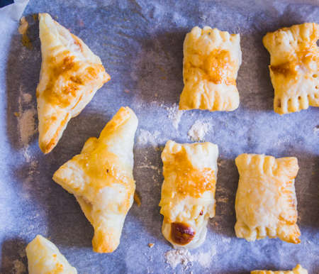 preparation of home-made savory snacks with puff pastry, mortadella, cheese and egg, cooked in the ovenの写真素材