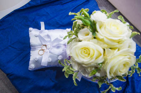 wedding rings on a white and soft pillow with beautiful and fragrant flowers, a symbol of love foreverの写真素材