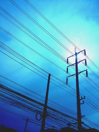 The sun behind power line postの素材