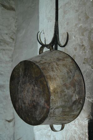 Metal cooking pot hanging by the fireplaceの写真素材