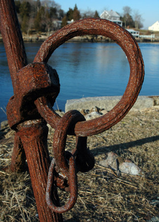 A rusty anchor ring offers a view of a narrow inlet