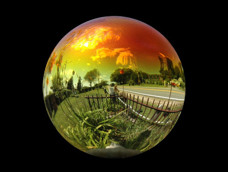 View of the summer sky through a roadside gazing ball