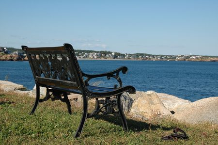 Black wrought iron bench and leather sandals sitting next to the Atlantic Ocean on a sunny summer dayの写真素材