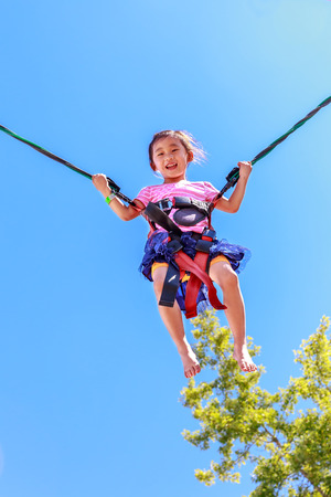 Little girl having a good time bungee jumping in county fair.の写真素材