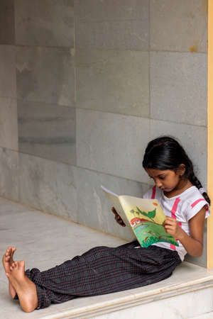 girl studying her lessons at home by reading bookの写真素材