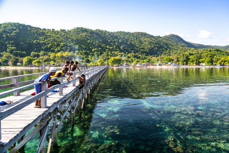 The Local Children Waiting to Swim in Clear Turquoise Water on A Long Wooden Pier