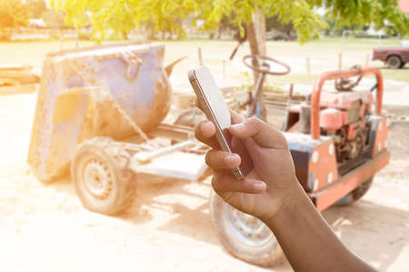 man hand hold and touch screen smart phone, tablet,cellphone on construction site in morning backgroundの写真素材