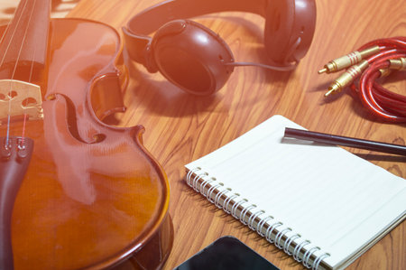 Violin phone notebook on wood background.Top view in music hipster tone.の写真素材