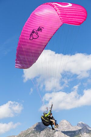INNSBRUCK, AUSTRIA - AUGUST 16,2013: Paraglider pink freedom in the sky near the mountain.のeditorial素材