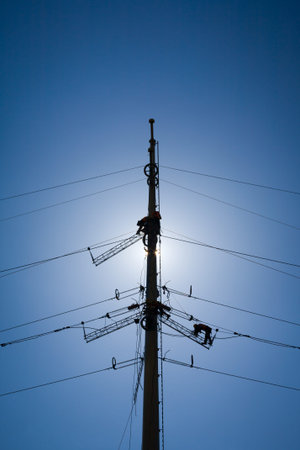 Worker repairing a high voltage industrial power energy line. No face is visible. Great for energy,...