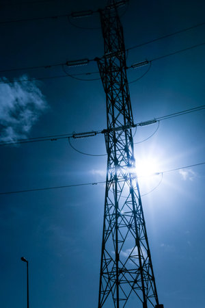 High tension electrical power lines and pylon tower against sky. Modern industrial energy line.