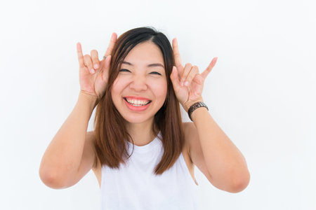 a joyful smiling asian girl with white undershirt is posing on the white backgroundの写真素材