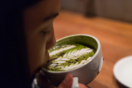 a girl is sipping the hot latte coffee in the morningの写真素材