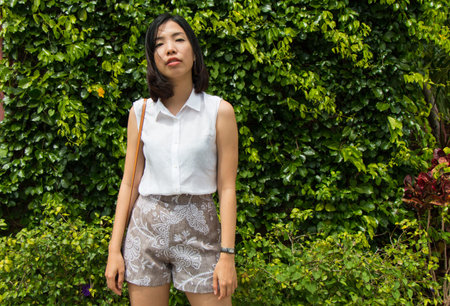 an asian young woman is standing with green nature background