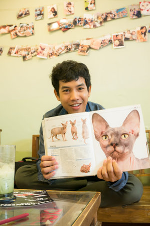 Boy reading book about cat race in home