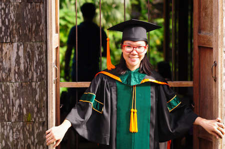 Asian graduated girl at wooden window in countrysideの写真素材