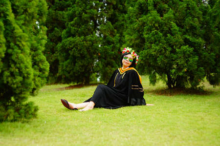 graduate with rainbow sunglasses in academic gownの写真素材