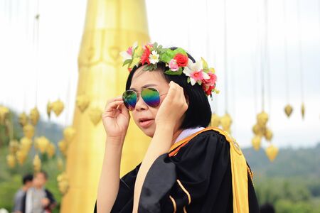 graduate with rainbow sunglasses in academic gownの写真素材