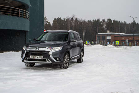 MOSCOW, RUSSIA - JANUARY 30, 2021 Mitsubishi Outlander. Third generation of Japanese compact crossover SUV produced by Mitsubishi Motors. Model year 2020. Dark Mitsubishi on winter background. Front side close up view.のeditorial素材