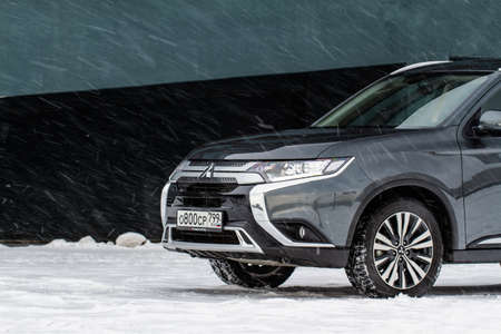MOSCOW, RUSSIA - JANUARY 30, 2021 Mitsubishi Outlander. Third generation of Japanese compact crossover SUV produced by Mitsubishi Motors. Model year 2020. Dark Mitsubishi on winter background. Front side close up view.のeditorial素材