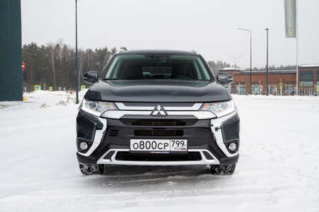 MOSCOW, RUSSIA - JANUARY 30, 2021 Mitsubishi Outlander. Third generation of Japanese compact crossover SUV produced by Mitsubishi Motors. Model year 2020. Dark Mitsubishi on winter background. Front side close up view.のeditorial素材