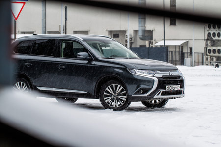 MOSCOW, RUSSIA - JANUARY 30, 2021 Mitsubishi Outlander. Third generation of Japanese compact crossover SUV produced by Mitsubishi Motors. Model year 2020. Dark Mitsubishi on winter background. Front side close up view.のeditorial素材