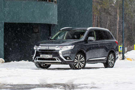MOSCOW, RUSSIA - JANUARY 30, 2021 Mitsubishi Outlander. Third generation of Japanese compact crossover SUV produced by Mitsubishi Motors. Model year 2020. Dark Mitsubishi on winter background. Front side close up view.のeditorial素材