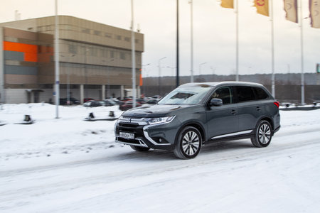 MOSCOW, RUSSIA - JANUARY 30, 2021 Mitsubishi Outlander in motion front side view. Third generation of Japanese compact crossover SUV produced by Mitsubishi Motors. Dark Mitsubishi on winter background.のeditorial素材